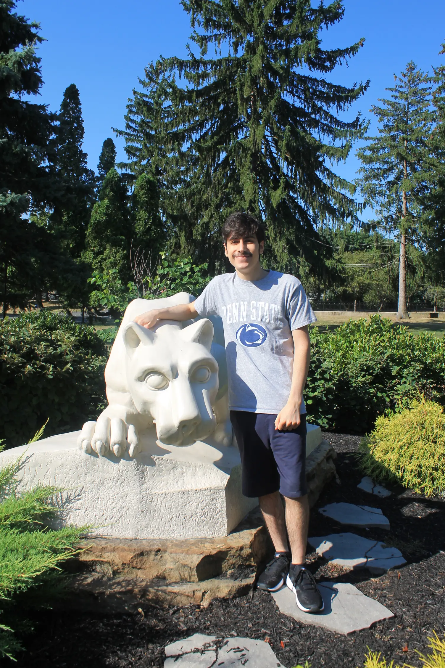 An image of Liam Ortiz in front of the Penn State lion